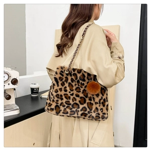 Detail of leopard print faux fur tote with woven chain strap and plush ball ornament