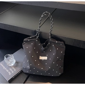 Détail du sac cabas en mousseline noire avec motif floral et poignées en corde rayées