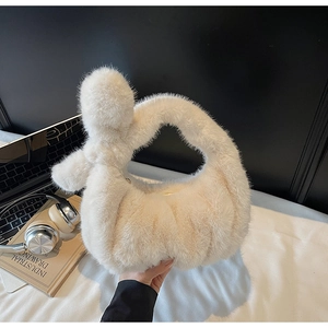 Détail du sac à main en peluche crème avec une poignée nouée élégante en fausse fourrure