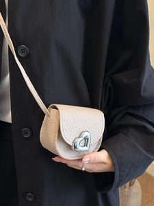 Chic cream mini crossbody bag with heart buckle and pebble texture on black coat