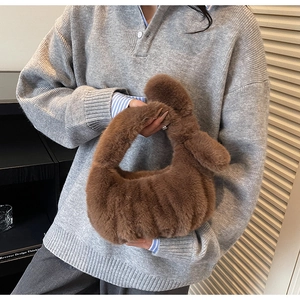 Gros plan du sac à main en peluche marron foncé avec une poignée nouée en fausse fourrure