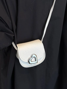 Mini white pebble leather saddle bag featuring a silver heart-shaped metal lock and strap