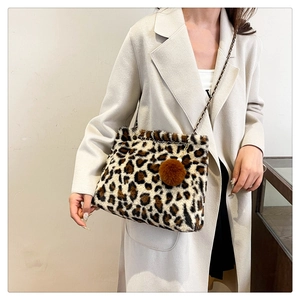 Detail of plush leopard print shoulder bag with metal chain strap and furry pompom charm