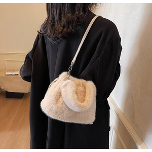 Détail d'un sac seau en fausse fourrure beige clair avec fine bandoulière en cuir