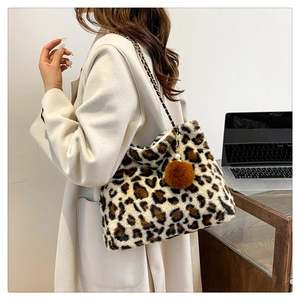 Detail of leopard print plush tote bag with gold chain strap and fluffy pompom charm