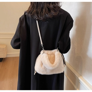 Détail du sac seau en fausse fourrure crème avec texture pelucheuse sur un manteau noir