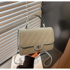 Detail of grey-green quilted leather handbag with silver turn-lock and chain strap