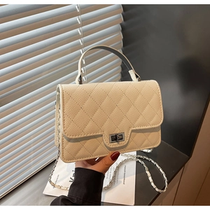 Detail of cream quilted leather handbag showing silver twist lock and chain strap