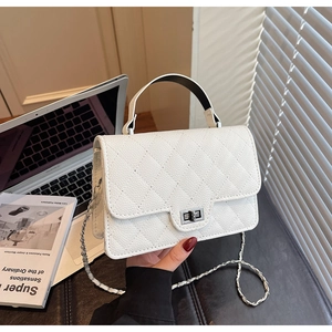 Detailed view of white quilted handbag with silver clasp and metallic chain strap