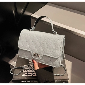 Detailed macro view of gray-blue quilted leather texture and metal turn-lock on the handbag