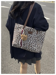Dettaglio della borsa tote leopardata con manici in pelle e ciondolo a orsetto
