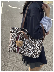 Borsa tote leopardata con cinturini in pelle marrone e ciondolo orsetto sul modello