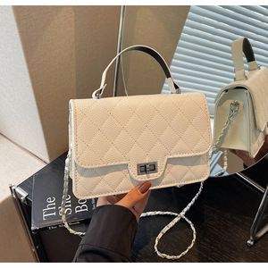 Close-up of white quilted leather texture with silver clasp and chain strap