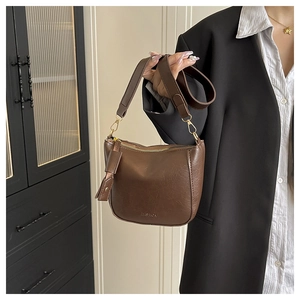 Detail van donkerbruine bucket bag met reliëflogo en een goudkleurige metalen ritssluiting
