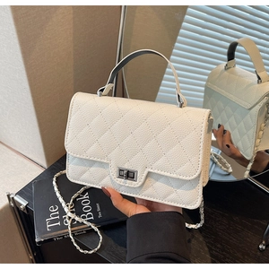 Close-up of white quilted leather texture and silver metallic twist lock on the handbag