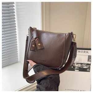 Detail van donkerbruine crossbodytas van imitatieleer met FASHION-logo en gouden metalen ritsen