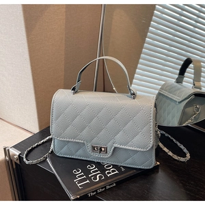 Detail of light blue quilted mini bag with silver rotating lock and leather chain strap