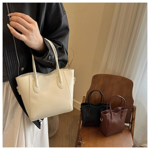 Detail of trendy textured leather tote bag with FASHION lettering and metal strap buckles