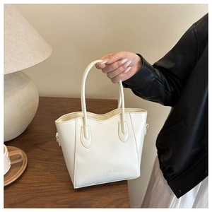 Close-up of a white leather tote bag featuring fashion letter embossing and top handles