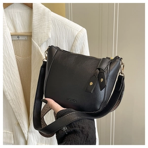 Detail van zwarte lederen crossbodytas met brede riem en goudkleurige hardware