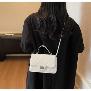 Rear view of a white quilted crossbody bag with chain strap on a black coat model