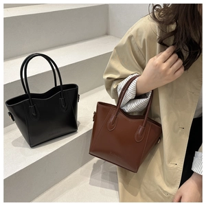Detail of classic tote bags in black and brown with FASHION embossed texture
