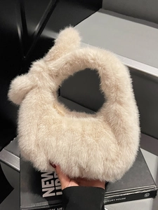 Sac à main chic en peluche beige avec poignée à nœud doux pour femmes sur escalier gris