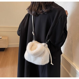 Détail d'un sac seau en fausse fourrure blanche avec cordon sur un manteau noir