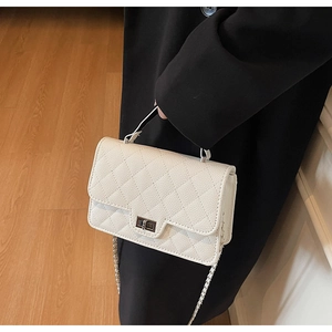 Close-up of white quilted leather crossbody bag with metal twist lock and chain strap