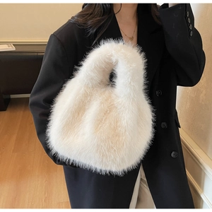 Gros plan d'un sac à main en fausse fourrure blanche porté par un mannequin en blazer