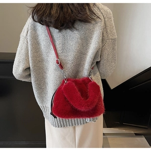 Détail du sac seau en fausse fourrure rouge avec bandoulière en cuir sur un mannequin