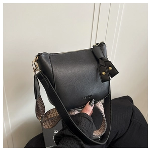 Detail van zwarte crossbodytas van imitatieleer met kleurrijke geweven schouderband