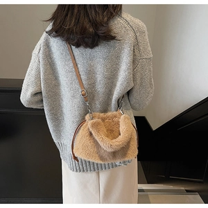 Détail du sac seau en peluche camel avec bandoulière sur un pull en maille grise