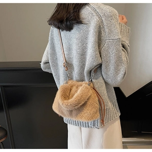 Détail du sac bandoulière en peluche camel avec lanière en cuir sur un pull gris