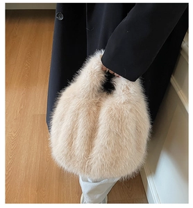 Détail d'un sac à main en peluche beige duveteux tenu par un mannequin en manteau noir