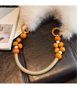 Détail de la bandoulière perlée avec des accents orange et fausse fourrure