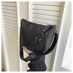 Detailweergave van zwarte PU-leertextuur en FASHION-logo in reliëf op de crossbodytas