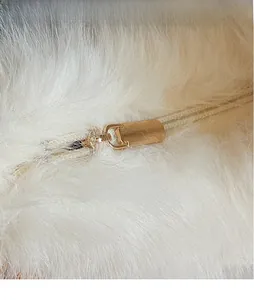 Gros plan d'une fermeture éclair en métal doré sur un sac à main en peluche blanche