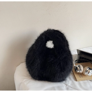 Détail de la texture en fausse fourrure douce et de l'anse du sac à main en peluche noir