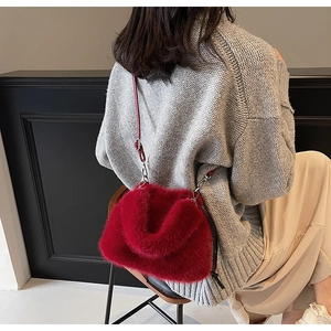 Détail du sac à bandoulière en fausse fourrure rouge porté sur un pull gris