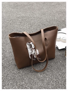 Flat lay of brown faux leather tote bag with silk scarf on street background