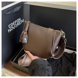 Detail van donkerbruine leren crossbodytas met FASHION-reliëf en geweven brede riem