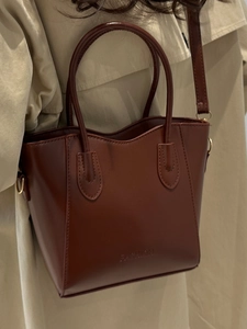 Deep brown leather bucket bag with top handles and adjustable strap for women