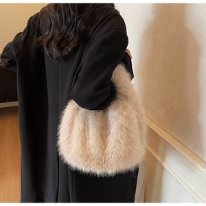Gros plan d'un sac cabas en fausse fourrure beige porté sur un manteau en laine noir
