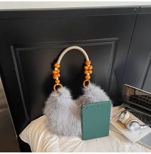 Détail du sac croissant en peluche grise avec poignée perlée et texture tissée