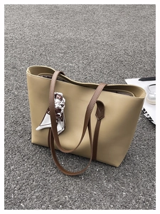 Close-up of khaki tote bag with brown straps and patterned silk scarf detail