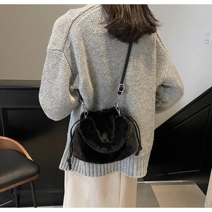Détail d'un sac seau en fausse fourrure noire avec cordon et bandoulière fine