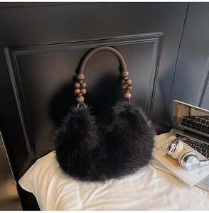 Détail du sac à main en fausse fourrure noire avec poignée tressée et perles en bois