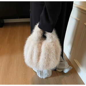 Détail du sac cabas en fausse fourrure beige porté avec un manteau noir élégant