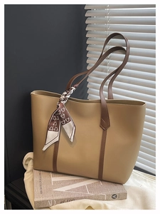 Detail of khaki tote bag with brown handles and a stylish printed silk scarf decoration